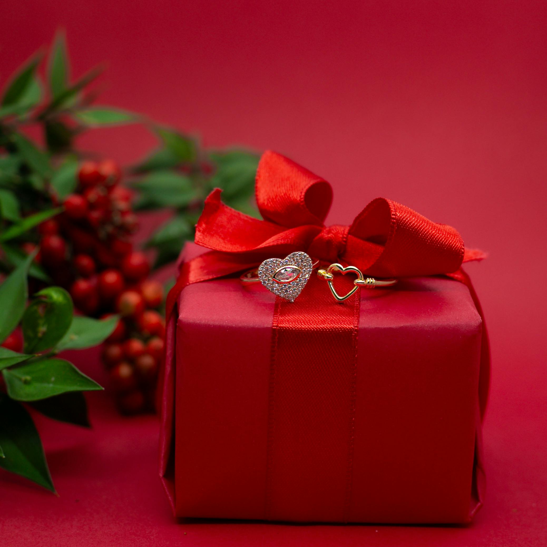 Red gift box with heart-shaped rings, perfect for Christmas and romantic celebrations.